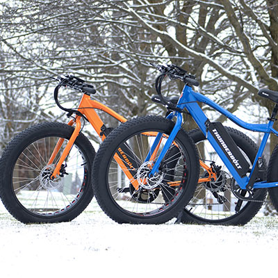 two fat tire e-bikes standing in the snow