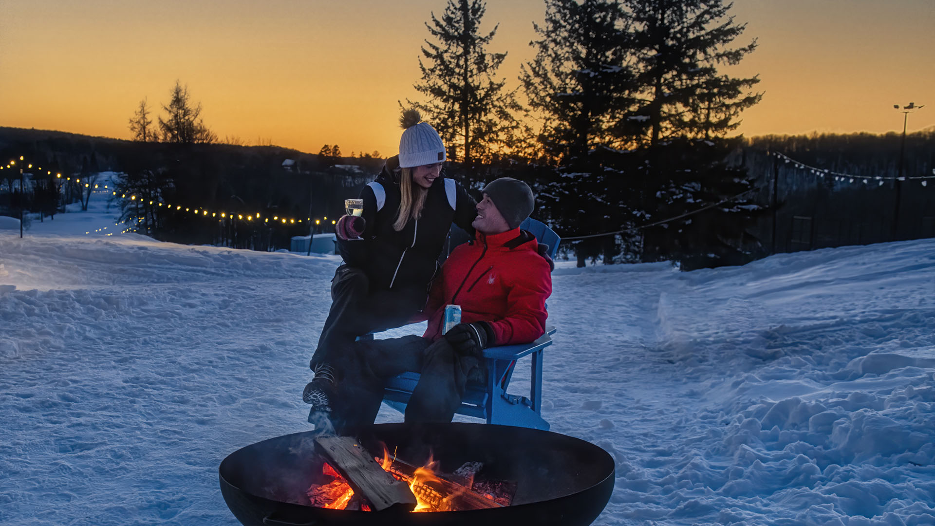 Couple sitting at campfire outside in winter