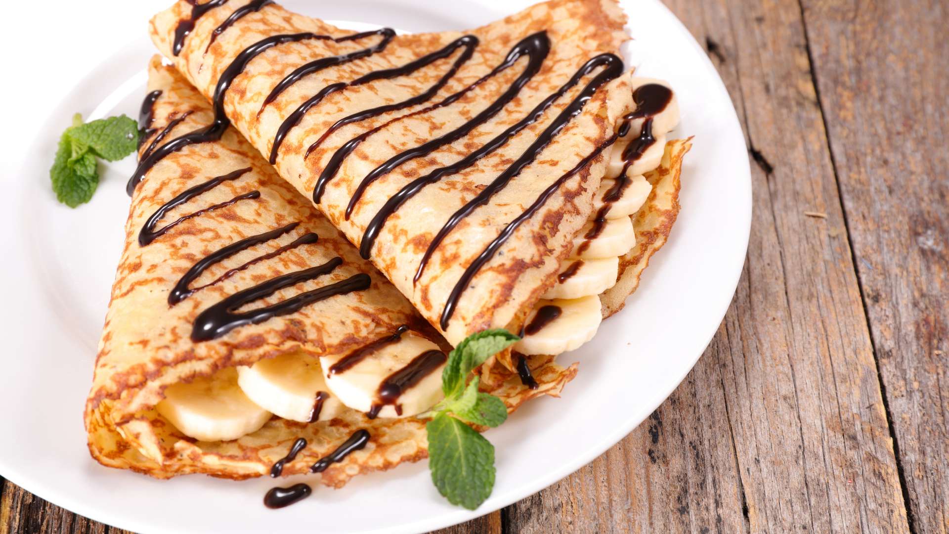 Crepes filled with banana drizzled with chocolate