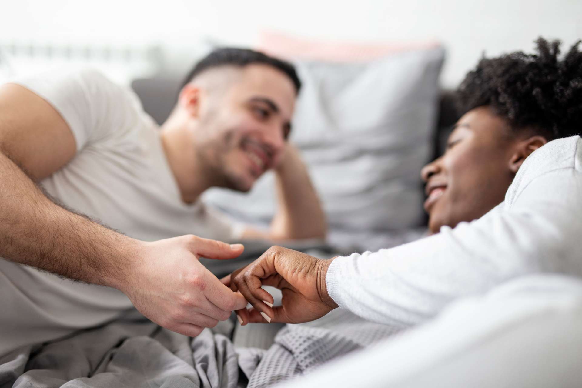 A couple holding hands laying in bed